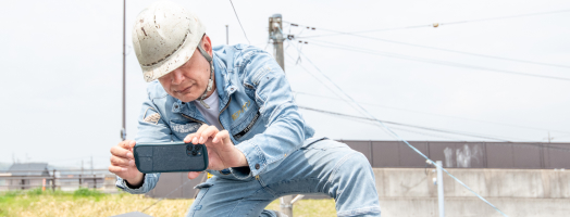 スマホカメラを構えるアイケン代表